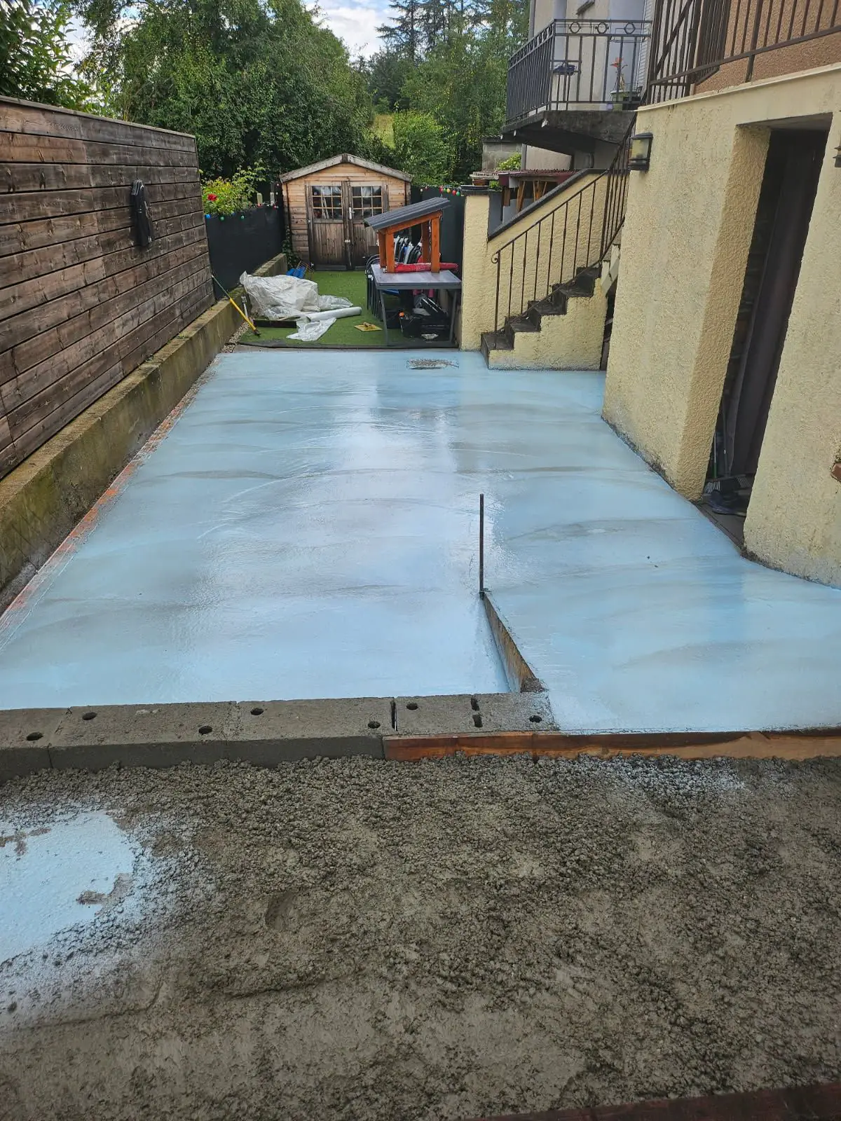 Dalle en béton désactivé fraîchement coulée le long d'une maison, avant rinçage